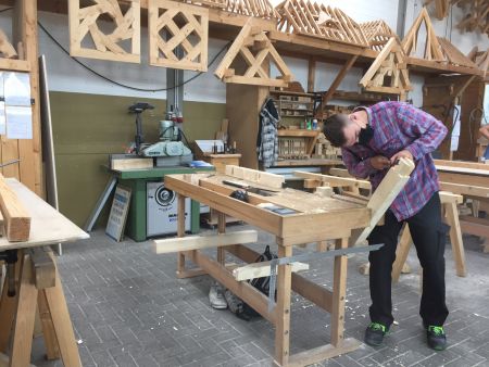 zu sehen ist ein junger Auszubildender mit einem Mundschutz, der in einer Werkstatt arbeitet